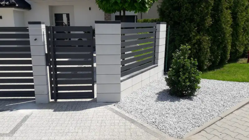 Ogrodzenie palisadowe poziome w kolorze antracytu z jasnymi słupkami z bloczków i furtką