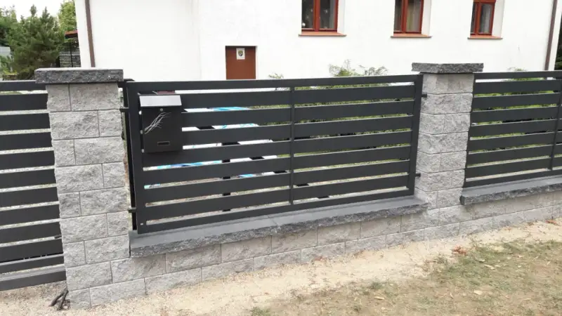 Ogrodzenie palisadowe z grafitowych profili między słupkami z łupanego kamienia